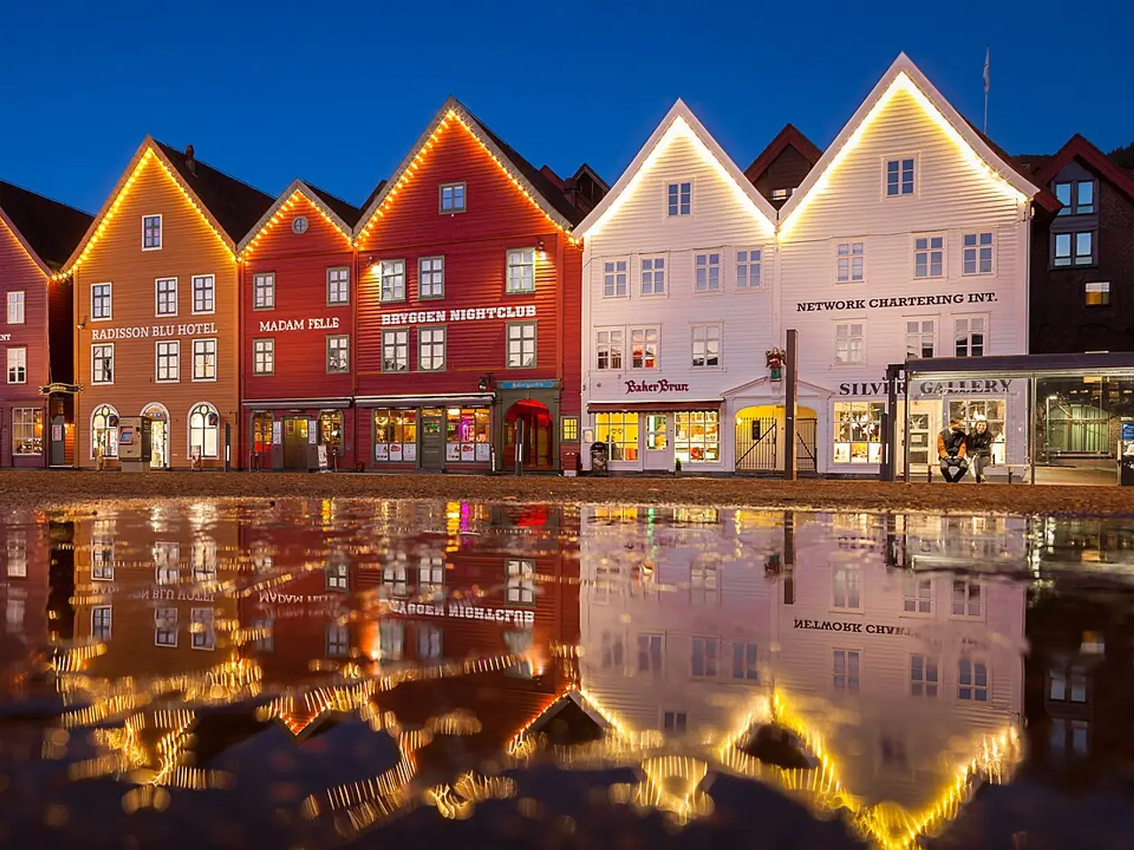 بيوت بريغن الخشبية الملوّنة تنعكس على الماء عند المساء